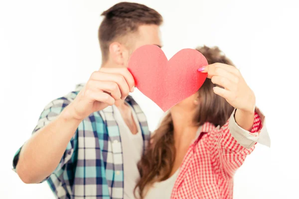 Fröhliches verliebtes Paar hält Papierherz und küsst — Stockfoto