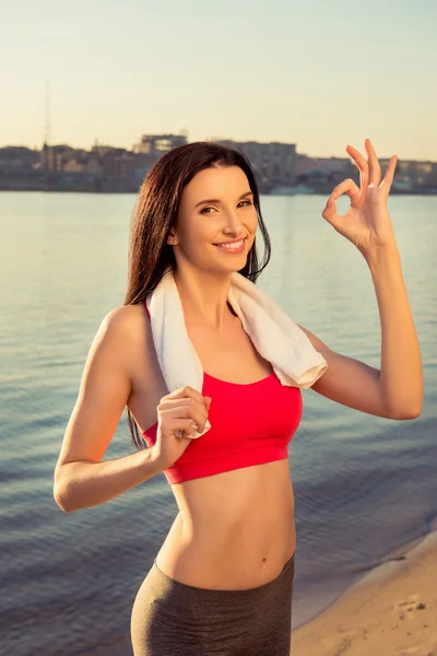 Seksowna szczupła kobieta pozowanie z ręcznikiem wskazując "OK" nad morzem — Zdjęcie stockowe