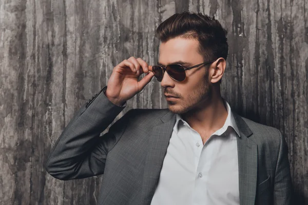 Portrait of trendy man in suit touching his spectacles — Stock Photo, Image