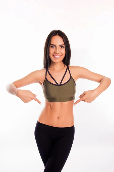 Joven mujer sana alegre en ropa deportiva apuntando sobre su vientre —  Fotos de Stock