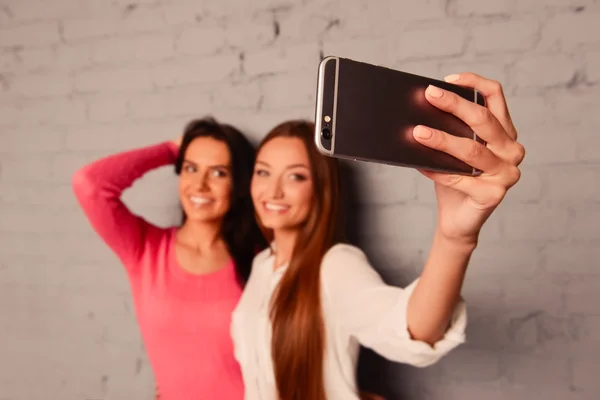 İki kız arkadaş cep telefonuyla selfie fotoğrafları çekiyor — Stok fotoğraf