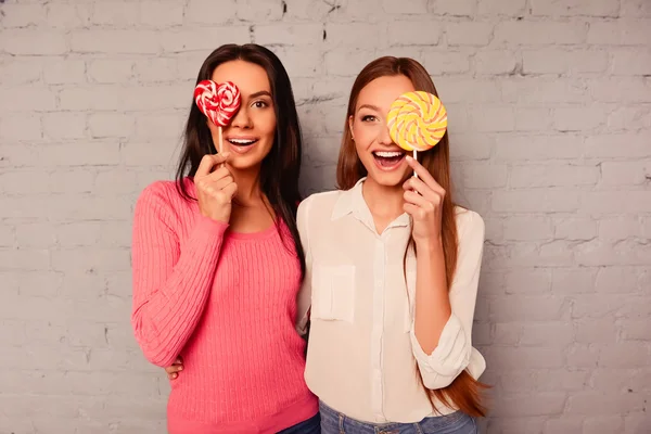 Zwei glückliche Mädchen freuen sich mit Lutscher und lächeln — Stockfoto