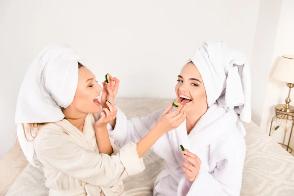 Funny young women with towels on their heads feeding ech other w — Stock Photo, Image