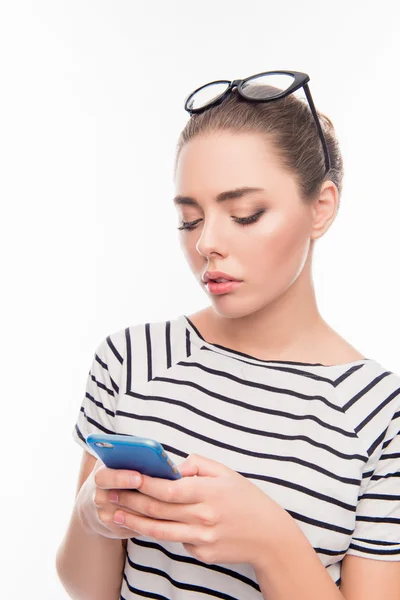 Minded young woman with glasses  typing sms on mobile phone — Stock Photo, Image