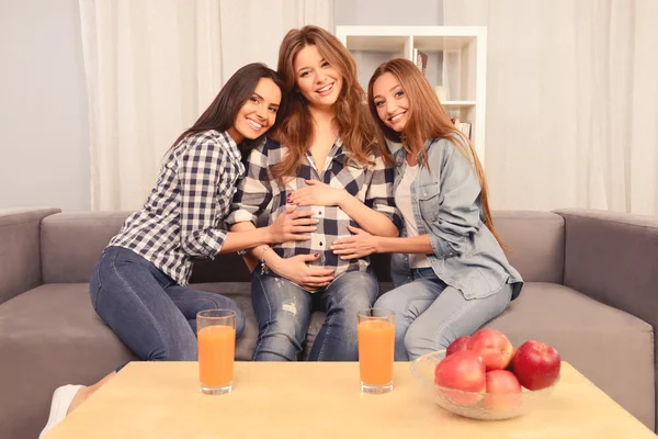 Hermosa mujer embarazada y sus amigas felices sentadas en tan — Foto de Stock