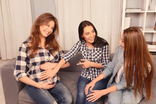 Meninas felizes e sua namorada grávida sentado no sofá e sm — Fotografia de Stock