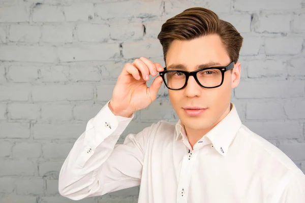 Attractive young man in white shirt touching his glasses — Stock Photo, Image