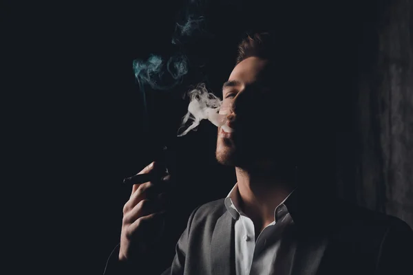Успешный бизнесмен с сигарой и дымом на черном фоне — стоковое фото