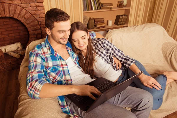 Beautiful couple in love  sitting on the sofa with laptop and sm — Stock Photo, Image