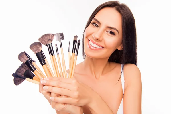 Retrato de chica con sonrisa radiante sosteniendo pinceles de maquillaje — Foto de Stock