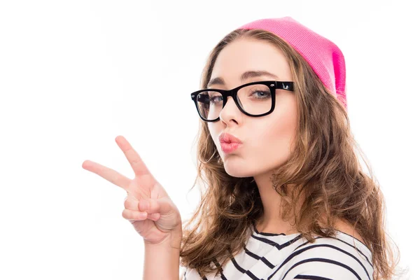 Mosolygó lány a kalap és a szemüveg, mutatja, két ujjal és duzzogás — Stock Fotó