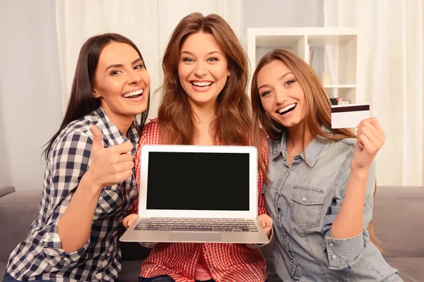 Glada tjejer visar laptop, bankkort och gester — Stockfoto