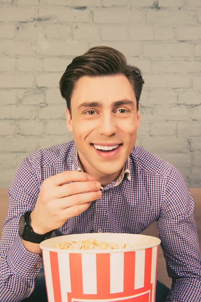 Retrato de feliz hombre sonriente comiendo palomitas de maíz en casa — Foto de Stock