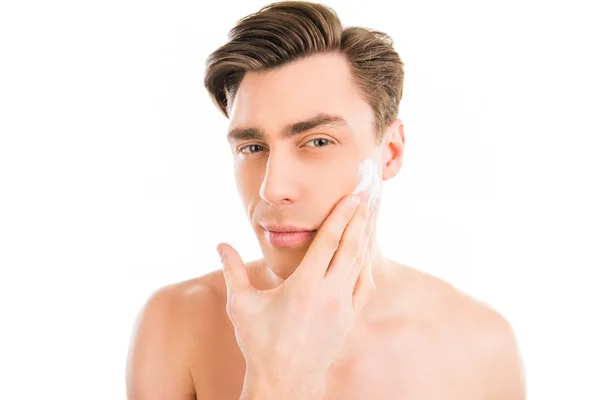 Красивый молодой человек со сливками для бритья на щеке — стоковое фото