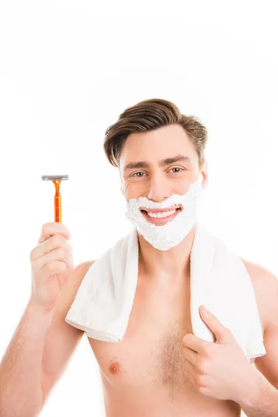 Cheerful handsome  man with towel and foam on his face holding r — Stock Photo, Image