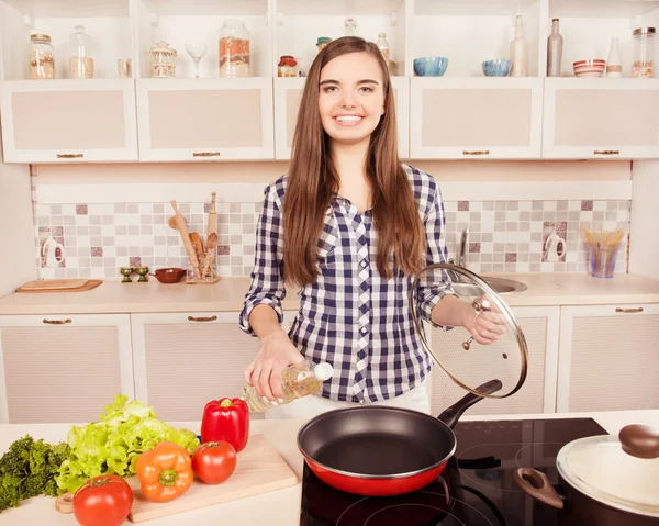 Vrolijk meisje gieten zonnebloemolie in de koekenpan — Stockfoto