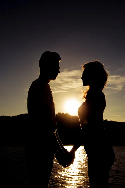 Silhouette della romantica coppia felice innamorata che si tiene per mano sul — Foto Stock