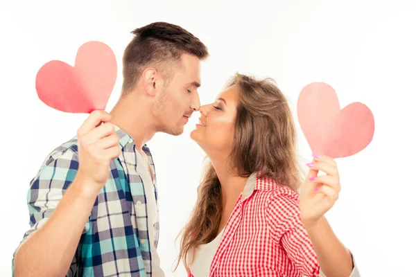 Ευτυχισμένο ζευγάρι ερωτευμένος κρατώντας δύο καρδιές χαρτί φιλιά μεταξύ τους — Φωτογραφία Αρχείου