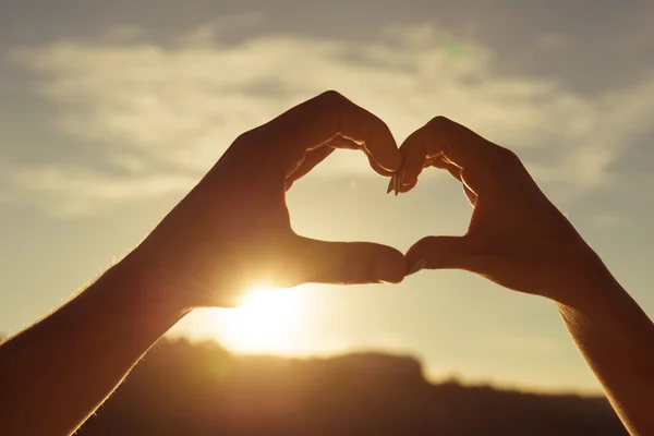 Pasangan romantis dalam cinta memberi isyarat hati dengan jari-jari di su — Stok Foto