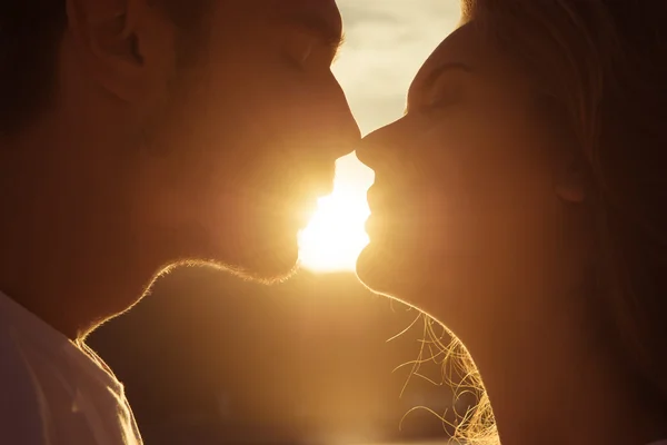 Blisko portret dwóch młodych kochanków całujących się na zachodzie słońca — Zdjęcie stockowe