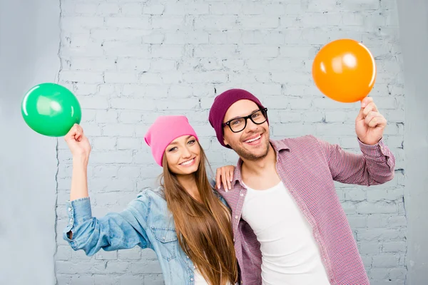 Positieve paar verliefd in caps en glazen houden ballonnen — Stockfoto