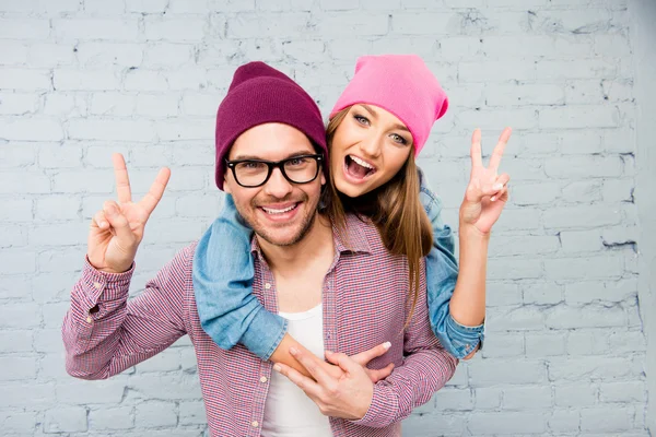 Feliz hombre y mujer alegres abrazando y haciendo gestos con dos fi — Foto de Stock