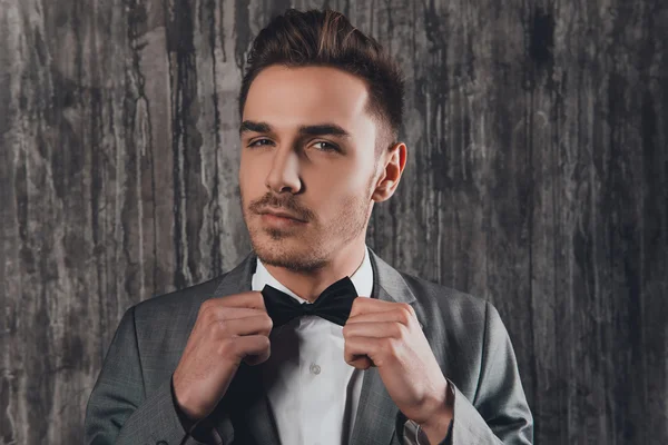 Close up portrait of  man in gray suit  fastening a bow-tie on h — Stock Photo, Image