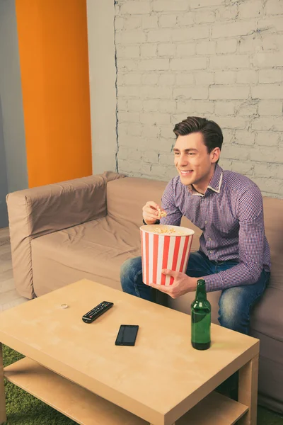 Feliz hombre sonriente viendo películas con palomitas de maíz y cerveza — Foto de Stock