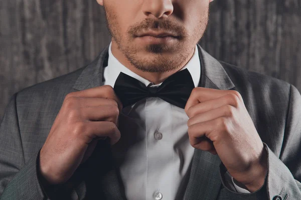 Close up portrait of young man fastening a bow-tie on his shirt — Stock Photo, Image