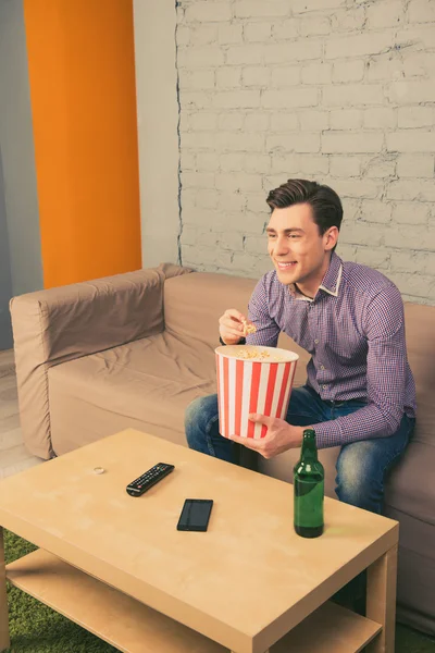 Feliz homem sorridente assistindo filme com pipocas e cerveja — Fotografia de Stock