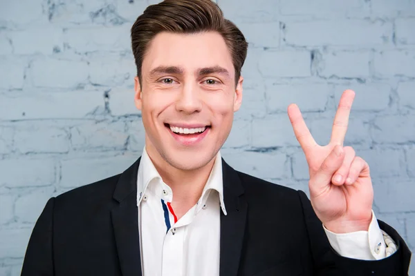 Portret van vrolijke jonge zakenman met twee vinger gebaren — Stockfoto