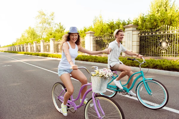 Ευτυχισμένο ζευγάρι στην αγάπη ιππασία ποδήλατα και κρατώντας τα χέρια — Φωτογραφία Αρχείου