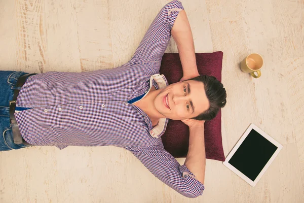 Закройте снимок улыбающегося человека, лежащего на полу, картинкой c — стоковое фото