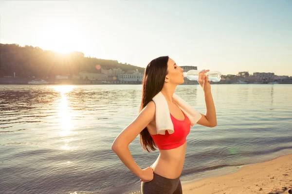Gesunde Frau mit Handtuch trinkt Wasser auf dem Hintergrund der — Stockfoto