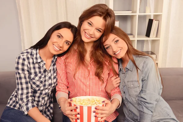 Портрет трех улыбающихся девушек, держащих ведро с попкорном — стоковое фото