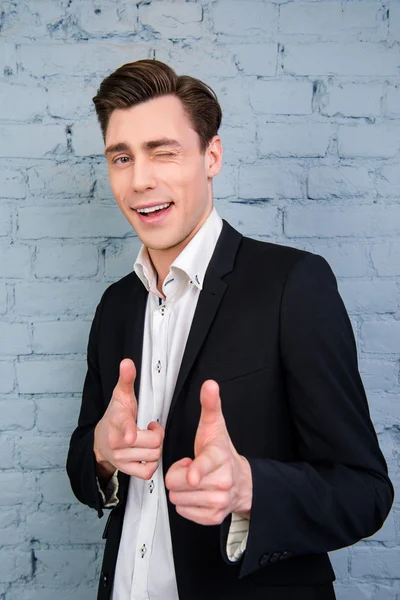 Portrait of handsome young businessman winking and pointing on c — Stock Photo, Image