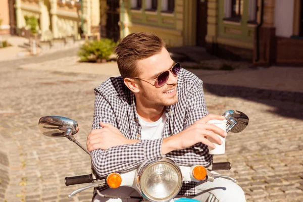 Sorrindo homem em óculos sentado na bicicleta e segurando café — Fotografia de Stock