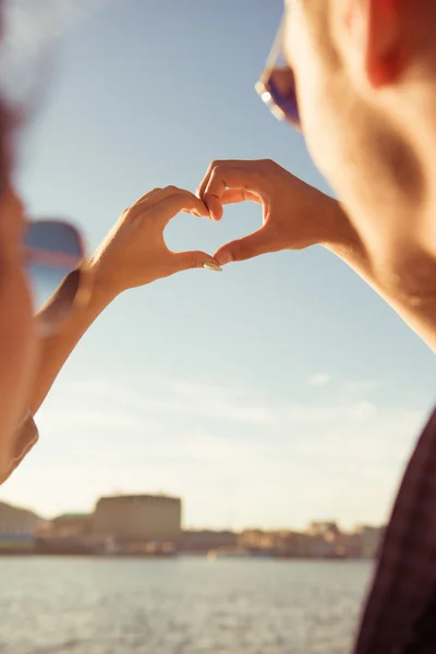 Pasangan dalam cinta memberi isyarat hati dengan jari di latar belakang — Stok Foto