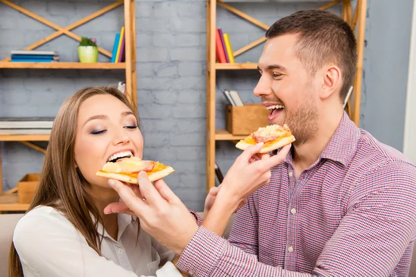Retrato de pareja feliz en el amor alimentándose mutuamente con pizza — Foto de Stock