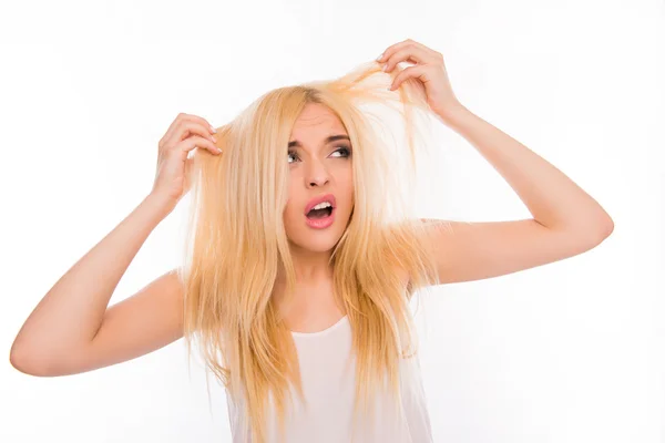 Verbaasd ongelukkige jonge vrouw haar beschadigde haren kijken — Stockfoto