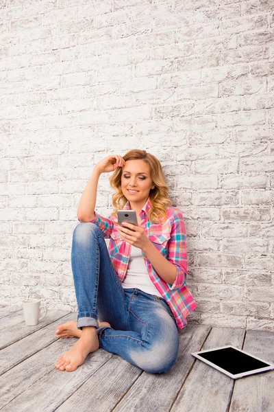 Szép nő ült a padlón, és gépelés üzenet-ra mozgatható telefon — Stock Fotó