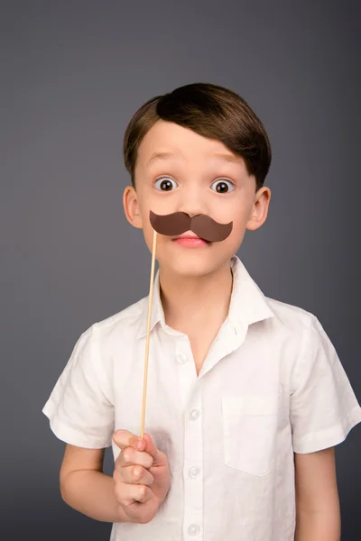 Retrato de niño bastante joven con bigote de papel sobre fondo gris —  Fotos de Stock