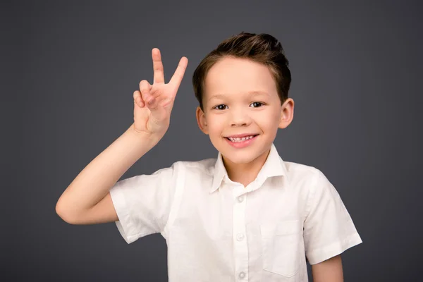 Liten glad rolig pojke gestikulerande med två fingrar — Stockfoto