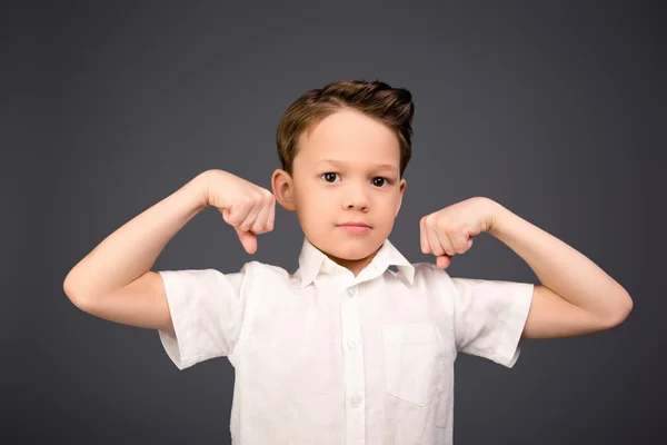 Niño pequeño con las manos levantadas mostrando sus músculos —  Fotos de Stock