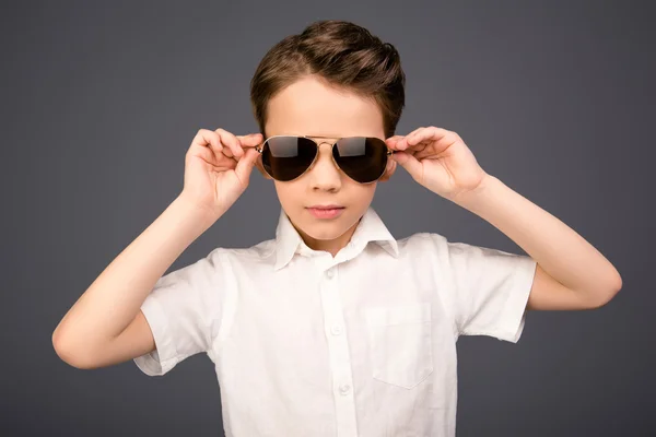 Snygg vacker liten skolpojke vidröra hans glasögon — Stockfoto