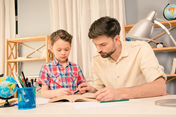 Fiatal apa, segít a kis fia, a házi feladat — Stock Fotó