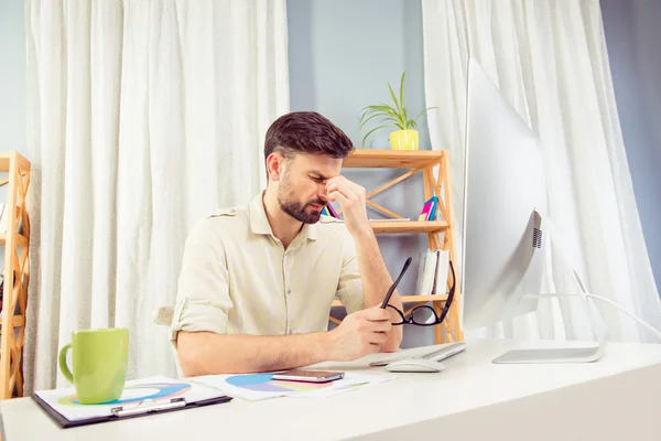 Depressive tired young man sitting in office and thinking — Stock Photo, Image