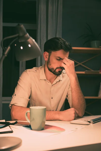 Depressiv överarbetade sinnad man sitter på natten i office — Stockfoto