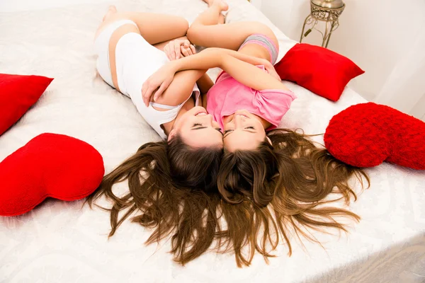 Meninas bonitas alegres de pijama abraçando uns aos outros e mentindo — Fotografia de Stock
