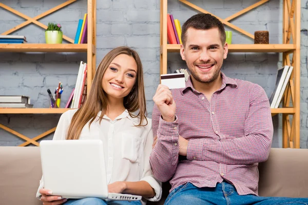 Hombre y mujer haciendo compras por Internet con computadora portátil y tarjeta bancaria — Foto de Stock